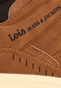 Zapatilla de ante marrón con costuras negras y logo grabado "Lois JEANS & JACKETS." Suela clara con acentos texturizados.