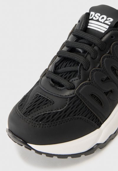Svarta sneakers som har en kombination av slät läder och mesh-material, med en strukturerad design, snören och en vit logotyp på tungan.
