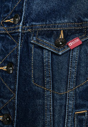 Teksatagi ees tasku nuppude kinnitusega, kollaste õmblustega ja punase kangast sildiga, millele on trükitud "BIG STAR".