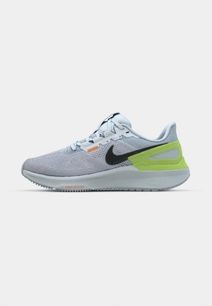 Nike running shoes in light gray mesh with black swoosh, green accent on heel, and orange detailing. Designed for comfort and support.