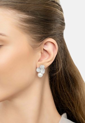 Silver flower-shaped earrings with crystal embellishments and a single white pearl drop. The design is detailed and elegant.