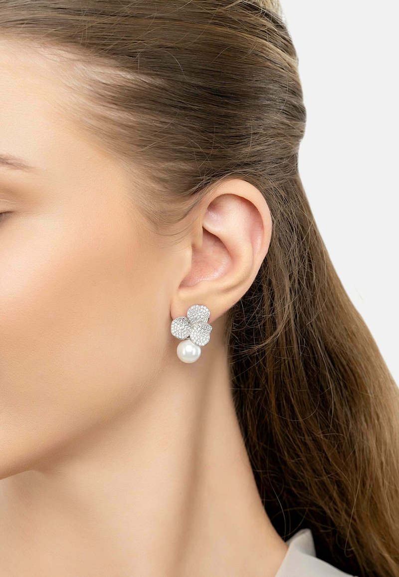 Silver flower-shaped earrings with crystal embellishments and a single white pearl drop. The design is detailed and elegant.