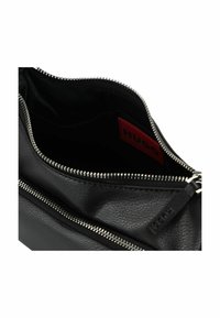 Bolso de piel negra con un acabado texturizado y cremallera plateada. El interior presenta una etiqueta de logo roja. Diseño compacto con un único compartimento principal.