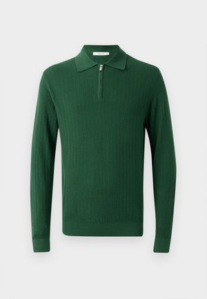 Tummanvihreä neulottu pitkähihainen polo-neule, jossa on vetoketjukaulus. Varustettu ribbitekstuuriin ja istuviin hihansuihin. Yksinkertainen muotoilu ilman kuvioita.