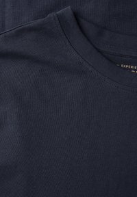 Camiseta de algodón azul marino con cuello redondo y textura suave, presentada en una posición de plano con mínimas arrugas.