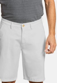 Pantalones cortos de algodón blancos con un corte recto, que cuentan con un cierre de botón dorado, dos bolsillos laterales y una textura suave.