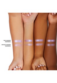 Trois bras présentent des échantillons de fard à paupières violet, avec et sans base. Les échantillons varient en éclat et en intensité selon les teintes de peau.