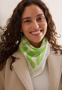 Grøn- og hvidmønstret tørklæde med teksten "I DAG VIL BLIVE EN FANTASTISK DAG", lavet af letvægtsstof, båret løst om halsen.