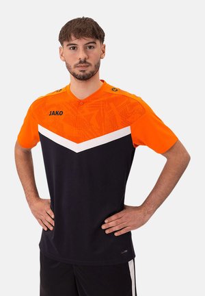 T-shirt de sport orange et marine avec un haut texturé, design en chevron blanc, col boutonné et logo "JAKO" sur la poitrine.