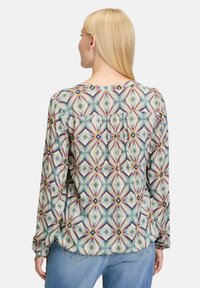 Long-sleeved blouse in lightweight fabric featuring a geometric pattern in pastel shades, with a pleated back and elastic cuffs.