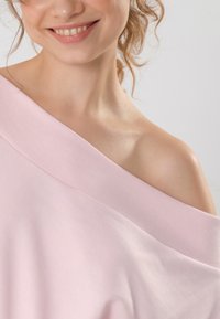 Top rosa chiaro off-the-shoulder con scollatura a coste; tessuto morbido e liscio; vestibilità rilassata; cuciture minime.