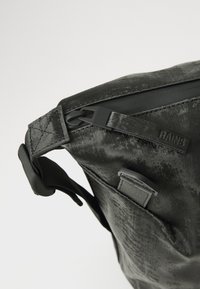Black waterproof messenger bag with a textured finish, featuring a plastic clasp and a subtle embossed logo. Includes a side pocket.