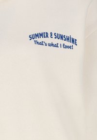 Cream-colored sweatshirt featuring blue text: "SUMMER & SUNSHINE" and "That's what I love!" in a playful, curved font. Soft texture.