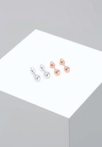 Par af studsøreringe, en i sølv og en i rosaguld. Hver har et minimalistisk design med kugleformede ender og en lige stang.