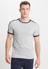 Graues Baumwoll-T-Shirt mit einem runden marineblauen Kragen. Verfügt über marineblaue Schulterakzente mit Markenlogo-Details. Figurbetontes Design.