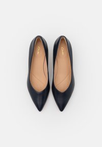 Chaussures à talons hauts en cuir bleu marine avec un bout pointu, une texture lisse et un design discret à découpes. L'intérieur présente de petites perforations pour la respirabilité.