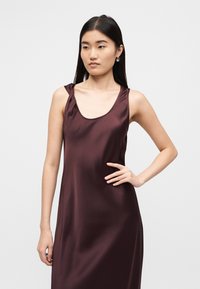 Φόρεμα από σατέν μπορντό με λαιμόκοψη scoop και στριφογυριστούς ιμάντες στους ώμους, με λεία υφή και άνετη, χαλαρή εφαρμογή.