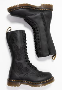 Černé kožené bojové boty s vyšitými vzory růží, šněrováním v přední části, zadním zipem a robustní, texturovanou podrážkou s oranžovým prošíváním.