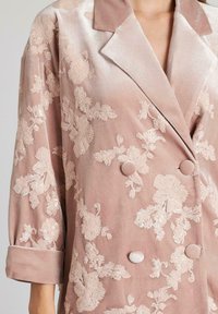 Blazer de terciopelo rosa con bordado floral, textura satinada, diseño de doble botonadura, dos botones cubiertos de tela y mangas remangadas.