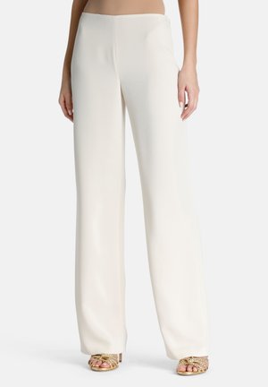 Weite Hosen aus weichem, cremigem Stoff mit glatter Textur und hoher Taille, kombiniert mit goldenen Sandalen mit Riemchen.