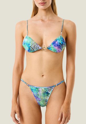 Donna che indossa un bikini multicolore con stampa animalier, spalline sottili e una fibbia circolare dorata al centro del top.