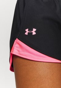 Pantalones cortos deportivos negros con un panel lateral rosa; hechos de tela texturizada; presenta un pequeño logo rosa de Under Armour en el dobladillo inferior izquierdo.