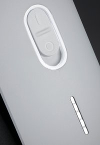 Gros plan sur un appareil gris avec un interrupteur à bascule ovale texturé et un indicateur LED vertical fin sur un fond sombre.