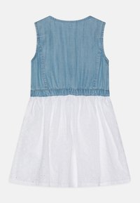 Dżinsowy gorset z marszczonym pasem, przechodzący w białą, teksturowaną spódnicę z wzorami w oczka. Bez rękawów, okrągły dekolt.