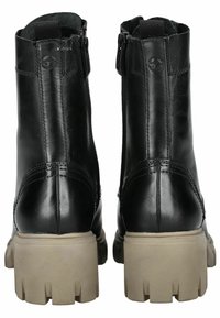 Botas de tobillo de cuero negro con una superficie texturizada, cremalleras laterales y suelas beige gruesas con un patrón de tacos.