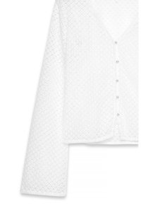 Balts, pogu veida kardigans, izgatavots no teksturēta, atvērtā adījumā. Tam ir V veida kakla izgriezums un garas piedurknes ar nedaudz īsāku apakšmalu.