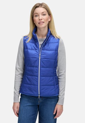 Blauer, gepolsterter Weste mit hohem Kragen, Reißverschluss vorne und horizontaler Steppstruktur. Getragen über einem grauen Langarmshirt.
