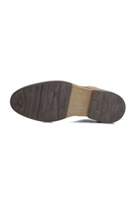Semelle de chaussure en cuir marron avec un motif de grip texturé, un insert en tan légèrement rembourré et une large zone pour les orteils pour plus de stabilité. Design plat.