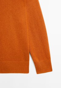 Orange gestrickter Pullover mit Rundhalsausschnitt, gerippten Bündchen und Saum. Weiche Textur mit nahtlosem Schulterdesign.