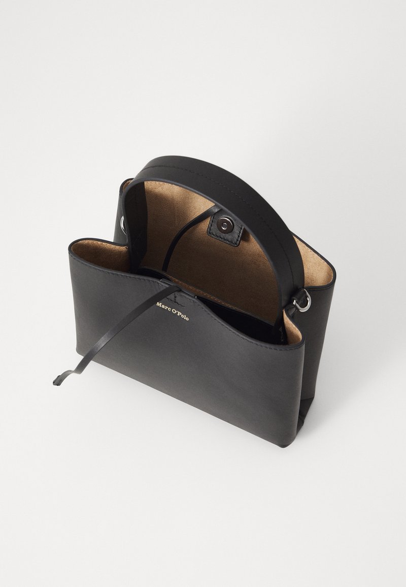 Schwarze Lederhandtasche mit glatter Oberfläche, abgerundetem oberen Ende und Innenfutter aus braunem Wildleder. Verfügt über einen kurzen Griff und ein minimalistisches Design.