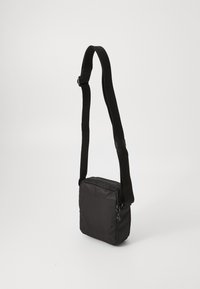 Bolso cruzado negro hecho de una tela texturizada, con un cierre superior con cremallera, correa ajustable y forma rectangular. Color sólido con un diseño minimalista.