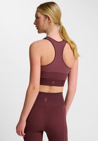 Bordeaux sportbeha met geribbelde textuur en racerback ontwerp, vergezeld van hoge taille bijpassende leggings met contrasterende stiksels.