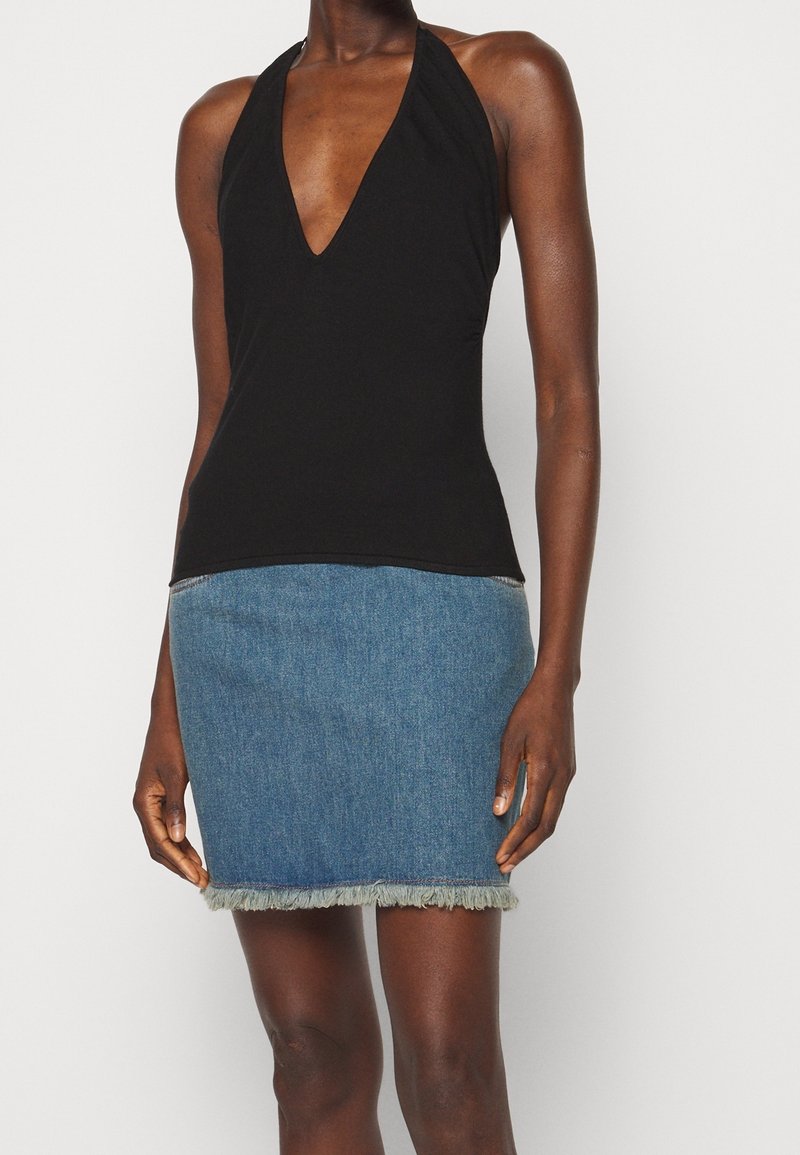 Haut noir à col licou avec un décolleté en V profond, associé à une mini-jupe en denim bleu avec un ourlet effiloché. Texture lisse et coupe ajustée.