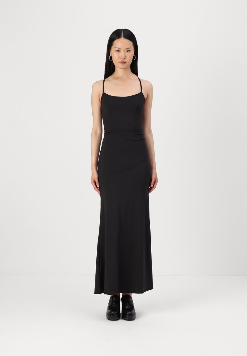 Črna, brezrokavna maksi obleka z oprijetim zgornjim delom, ravnim dekoltejem, tekočim krilom in subtilno raztegljivostjo. Nosi se z črnimi platform čevlji.