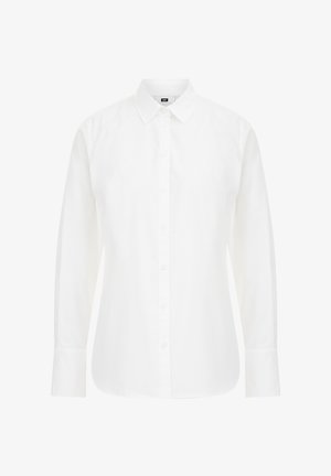 Chemise blanche à manches longues en coton, avec un col classique, des boutons sur le devant et un ourlet droit aux bords légèrement arrondis.
