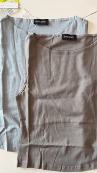 Two folded sleeveless tops, one light gray and one taupe, both with round necklines and Even & Odd brand labels on white surface.