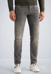 Sivé denimové džínsy so slim fit strihom, mierne vyblednutou textúrou, s prednými vreckami a logom na páske. Skombinované s bielymi teniskami.