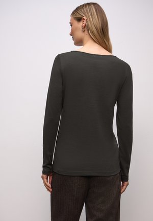 Maglietta a maniche lunghe di colore verde scuro con una texture morbida e collo ampio, abbinata a pantaloni marroni dalla texture irregolare. Design minimalista senza decorazioni.