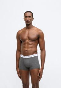 Szürke boxeralsó fehér elasztikus derékpánttal, amelyen a "GANT" logó látható. Sima anyagból készült, testhez álló szabású, a kényelem érdekében szabva.