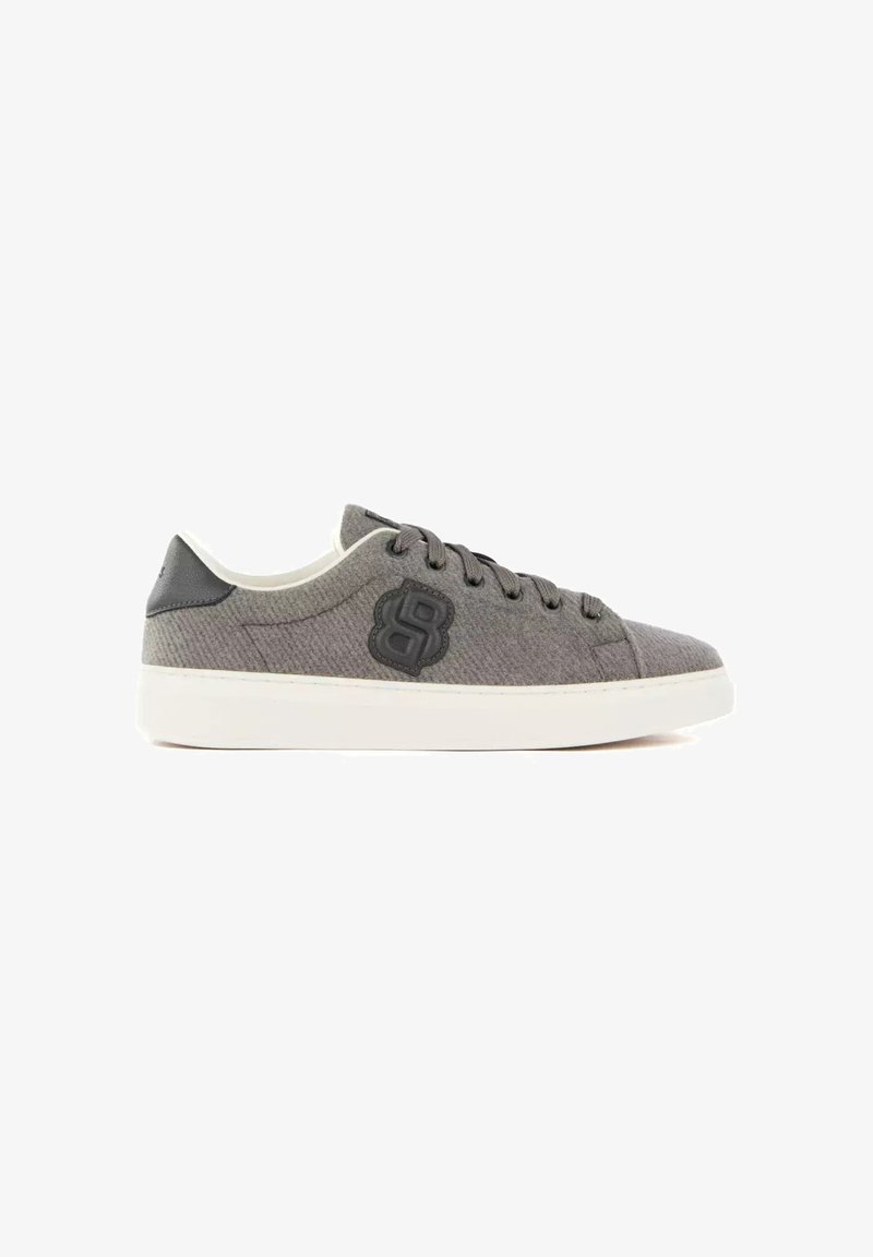 Baskets basses grises en tissu avec patch logo noir, lacets gris, détail noir au talon et semelle en caoutchouc blanche, présentées sur fond blanc.