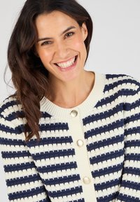 Maritiem en roomkleurig gestreepte cardigan met een gestructureerd breisel, ronde halslijn en grote knopen aan de voorkant.