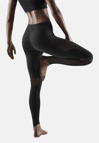 Leggings de sport noirs avec panneaux en maille, taille haute et design sans couture. Pied de couleur peau visible, mettant en avant l'ajustement et la flexibilité.