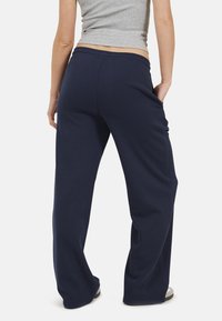 Pantaloni della tuta blu navy con una vestibilità comoda, cintura elasticizzata e tasche laterali; realizzati in un tessuto morbido e testurizzato.