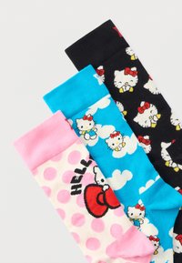 Τρία ζευγάρια πολύχρωμες κάλτσες με πρόσωπα Hello Kitty και φιόγκους, με πουά, σύννεφα και διαφορετικά χρώματα φόντου.