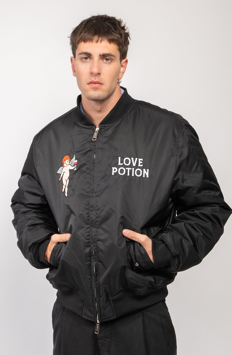 Black bomber jacket with a smooth texture, featuring "LOVE POTION" lettering and an embroidered cherub design on the left chest.