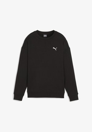 Zbliżenie osoby noszącej czarną bluzę Puma i niebieskie dżinsy, skupiające się na dolnej części pleców i szczegółach ubrania.